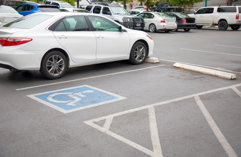 white car parked next to an empty handicap parking spot